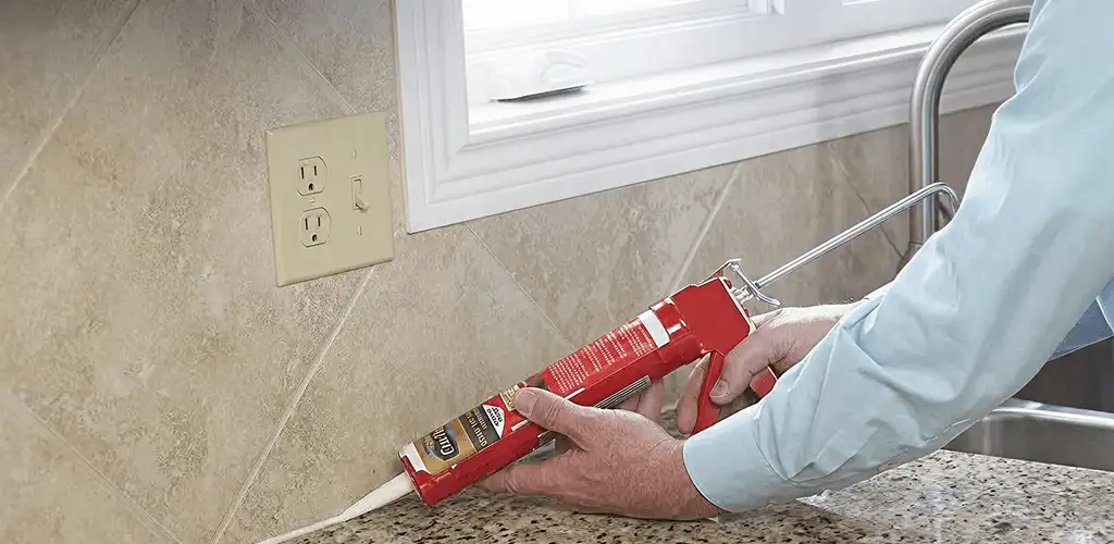Handyman applying caulk along a kitchen backsplash and countertop seam in Reno, NV