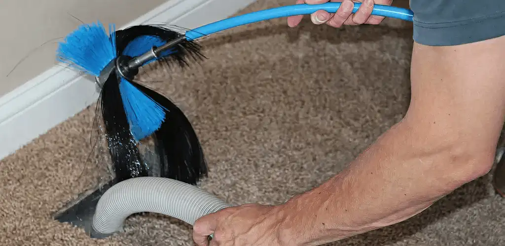Dryer vent cleaning technician brushing lint from a vent line in Reno, NV