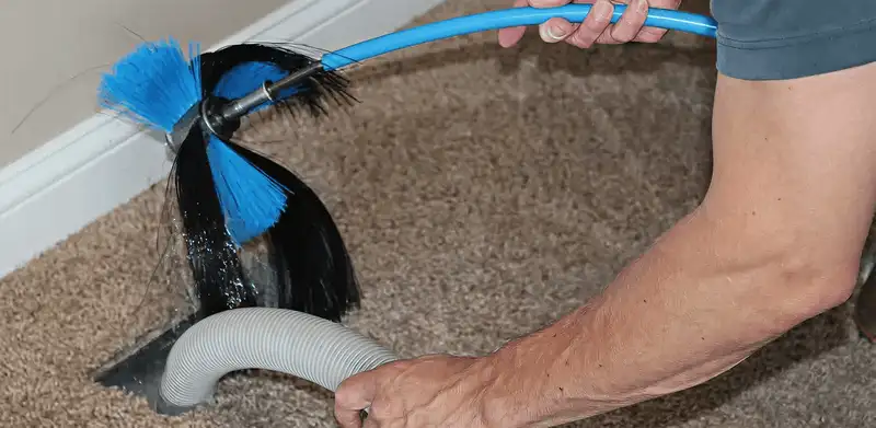 Dryer vent cleaning technician brushing lint from a vent line in Reno, NV