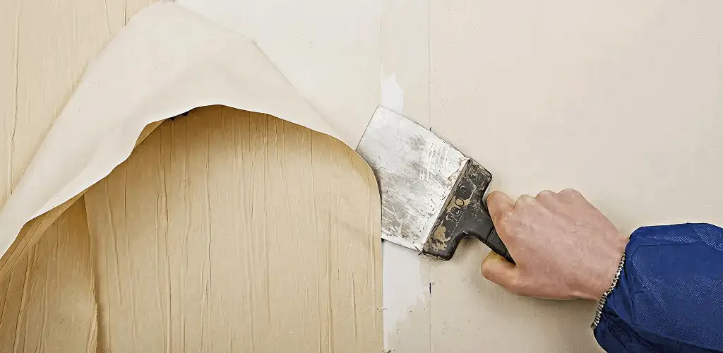 Handyman removing wallpaper with a scraper for wall preparation in Reno, NV